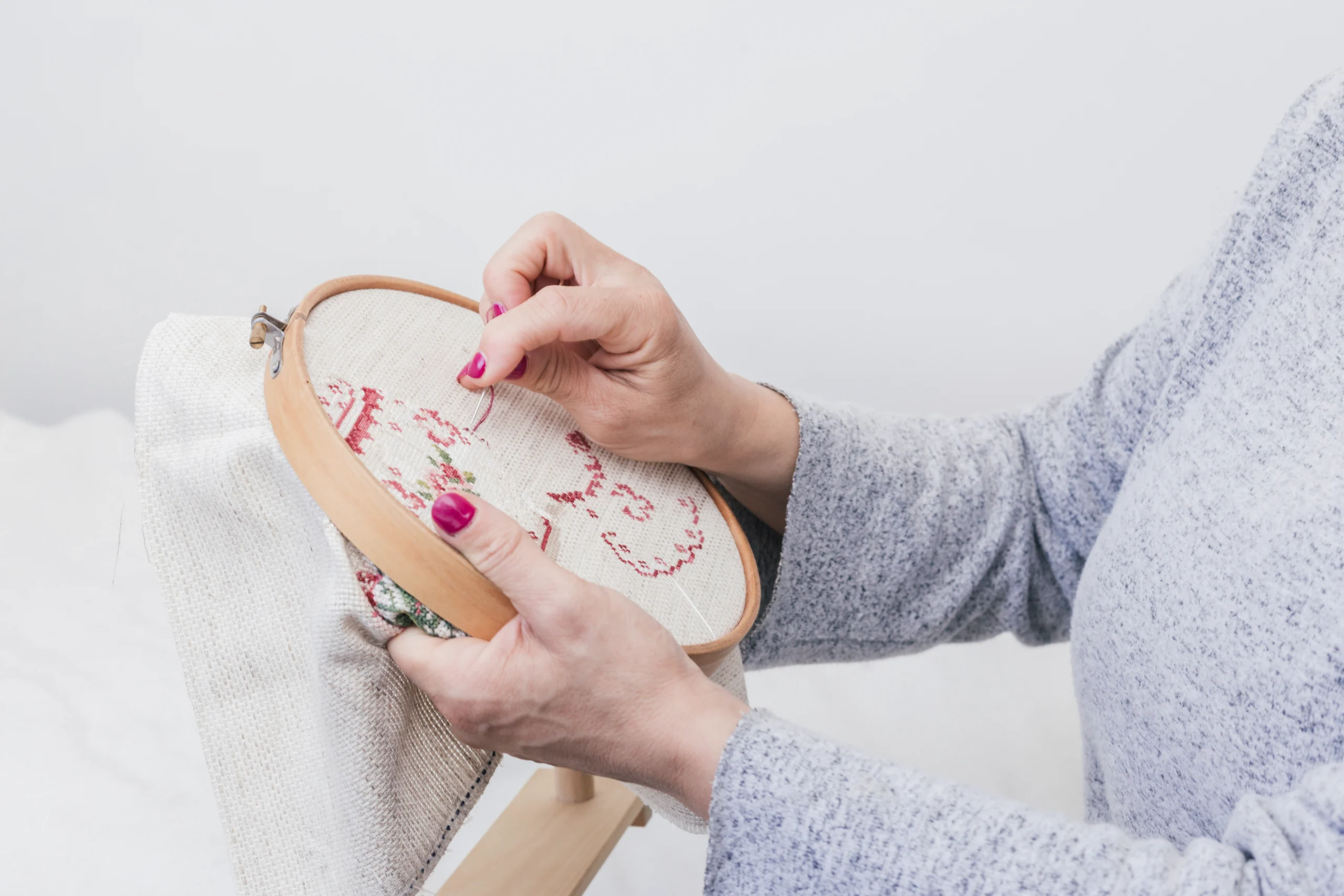 woman s hand cross stitching pattern hoop against white background scaled