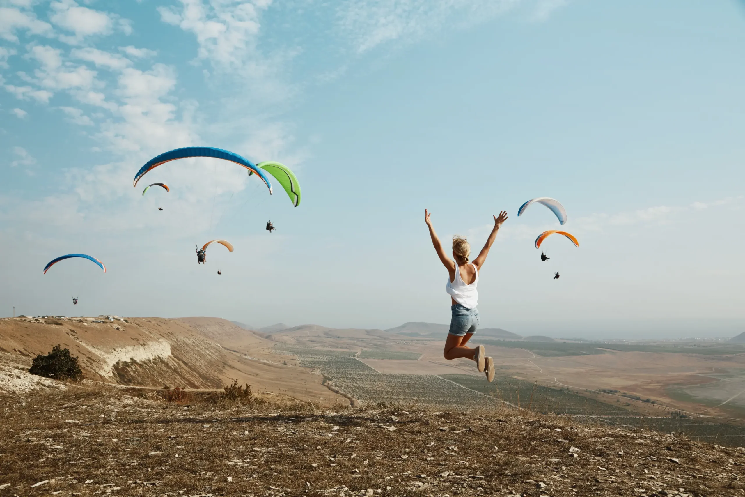 young blonde woman jumping top hill scaled